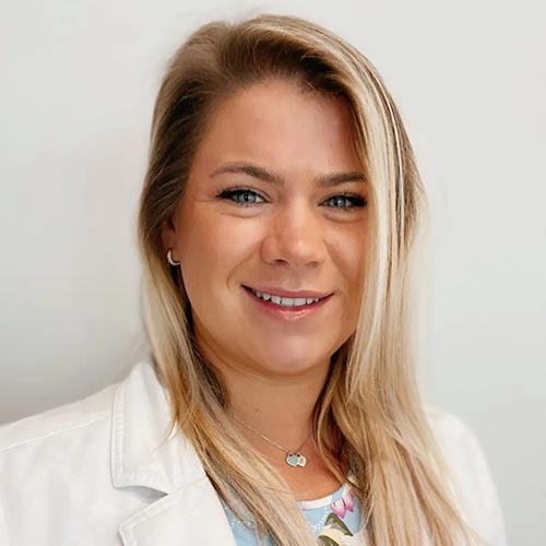Dr Tonsich wearing a white lab coat and smiling at the camera