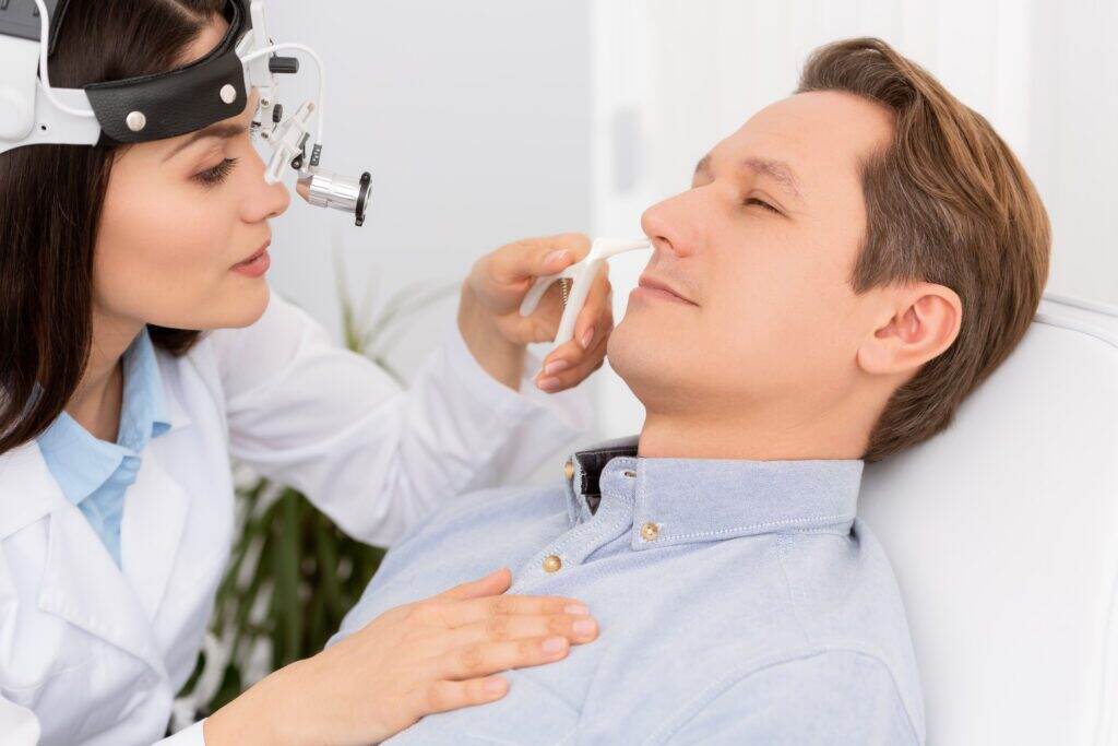 man getting her nose looked at by a doctor