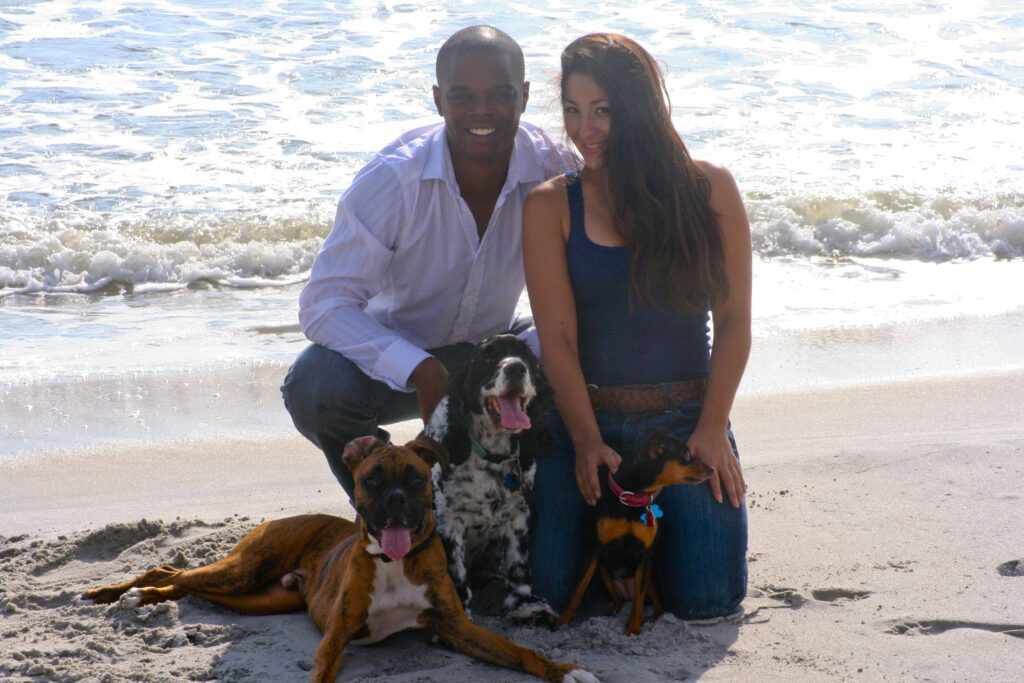 woman and man on the beach with their three dogs