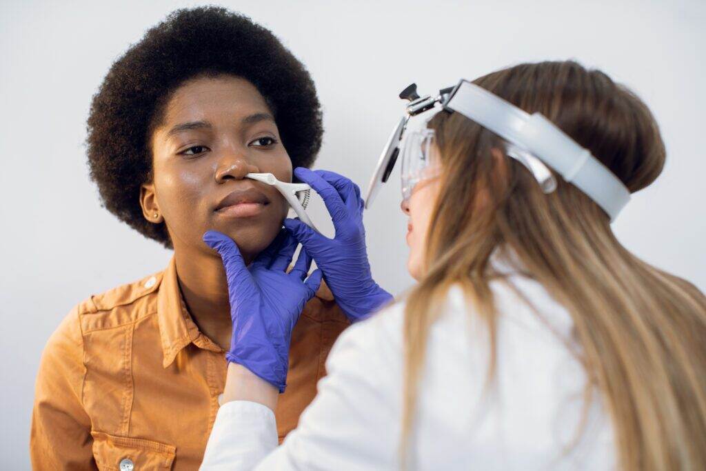 woman getting her nose looked at by the doctor