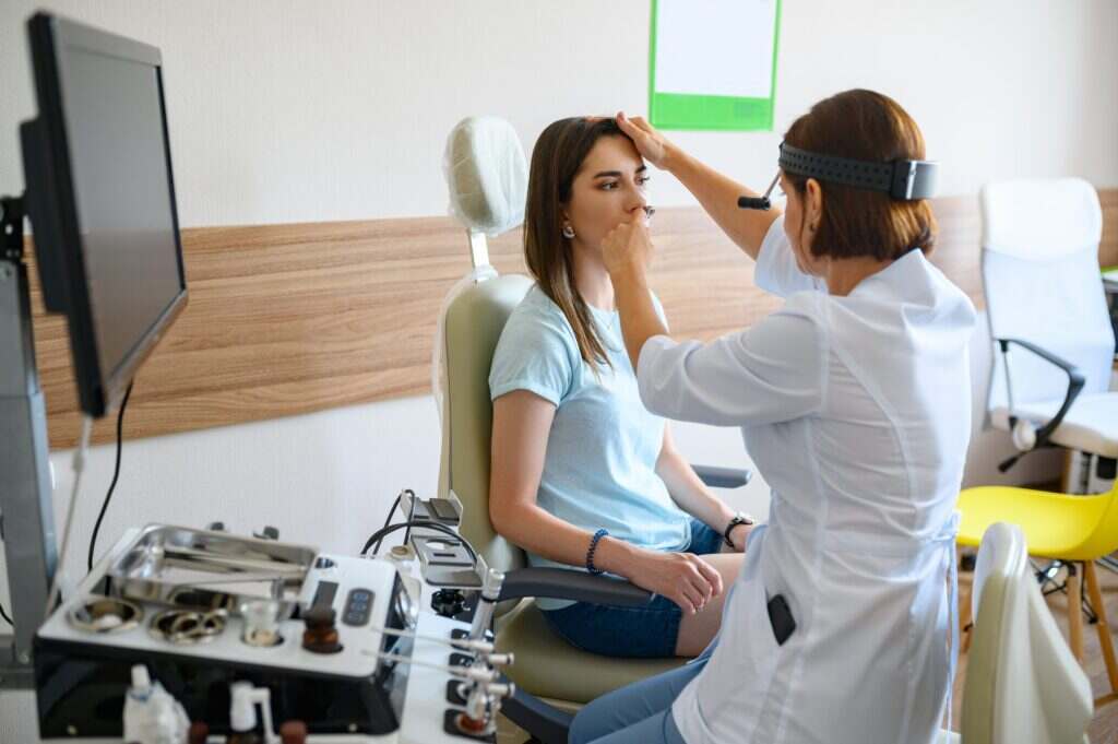 woman getting her nose looked at by the doctor