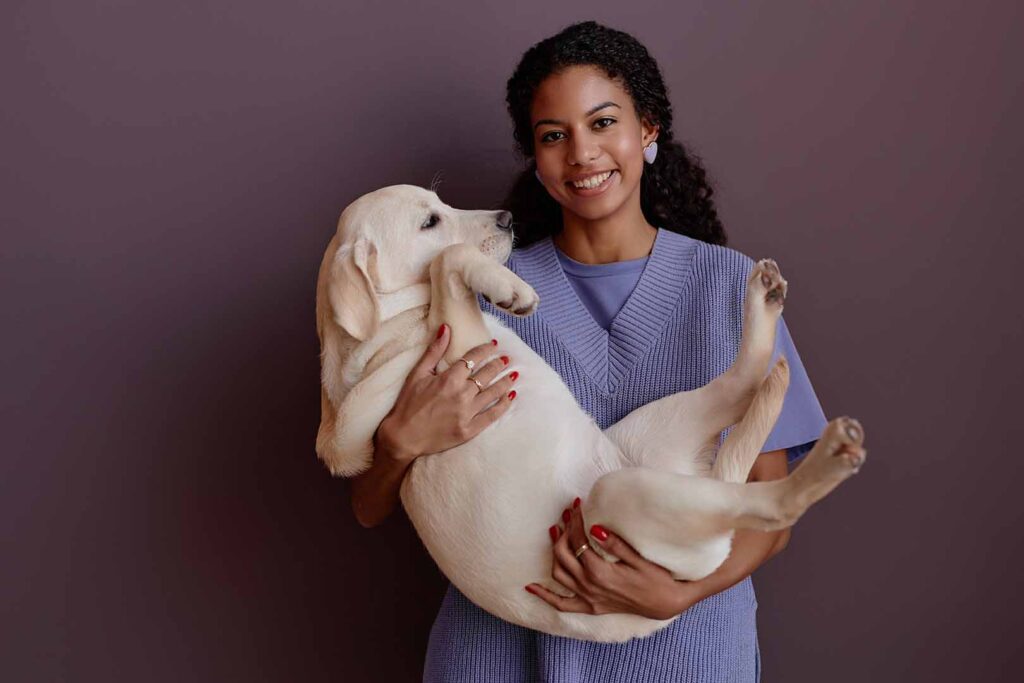 woman wearing a purple sweater holding a white dog