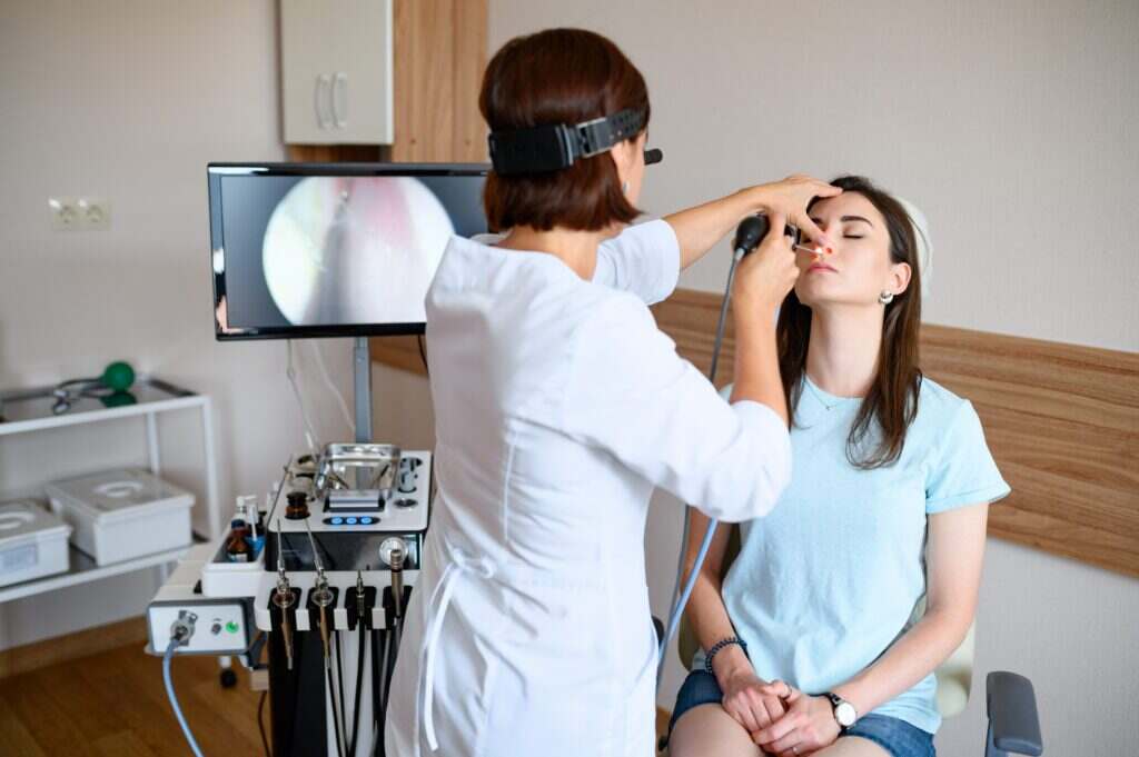 woman getting her nose looked at by a doctor