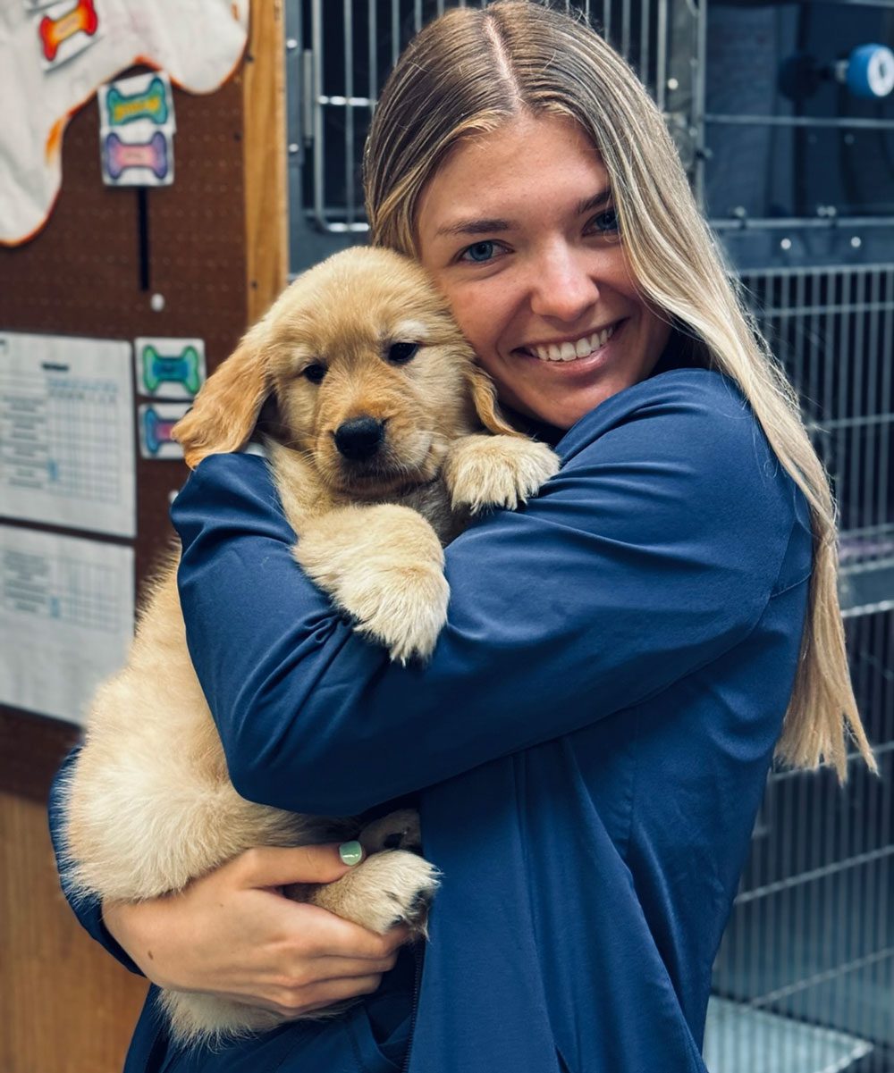 Vet Assistant Hugging Small Pup While Smiling