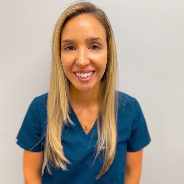 Alejandra Claypool wearing blue scrubs and smiling at the camera