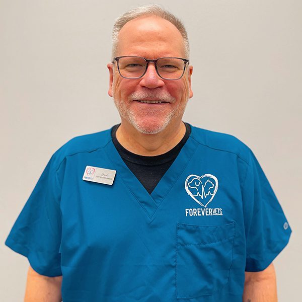 David Hucks wearing blue scrubs and smiling at the camera