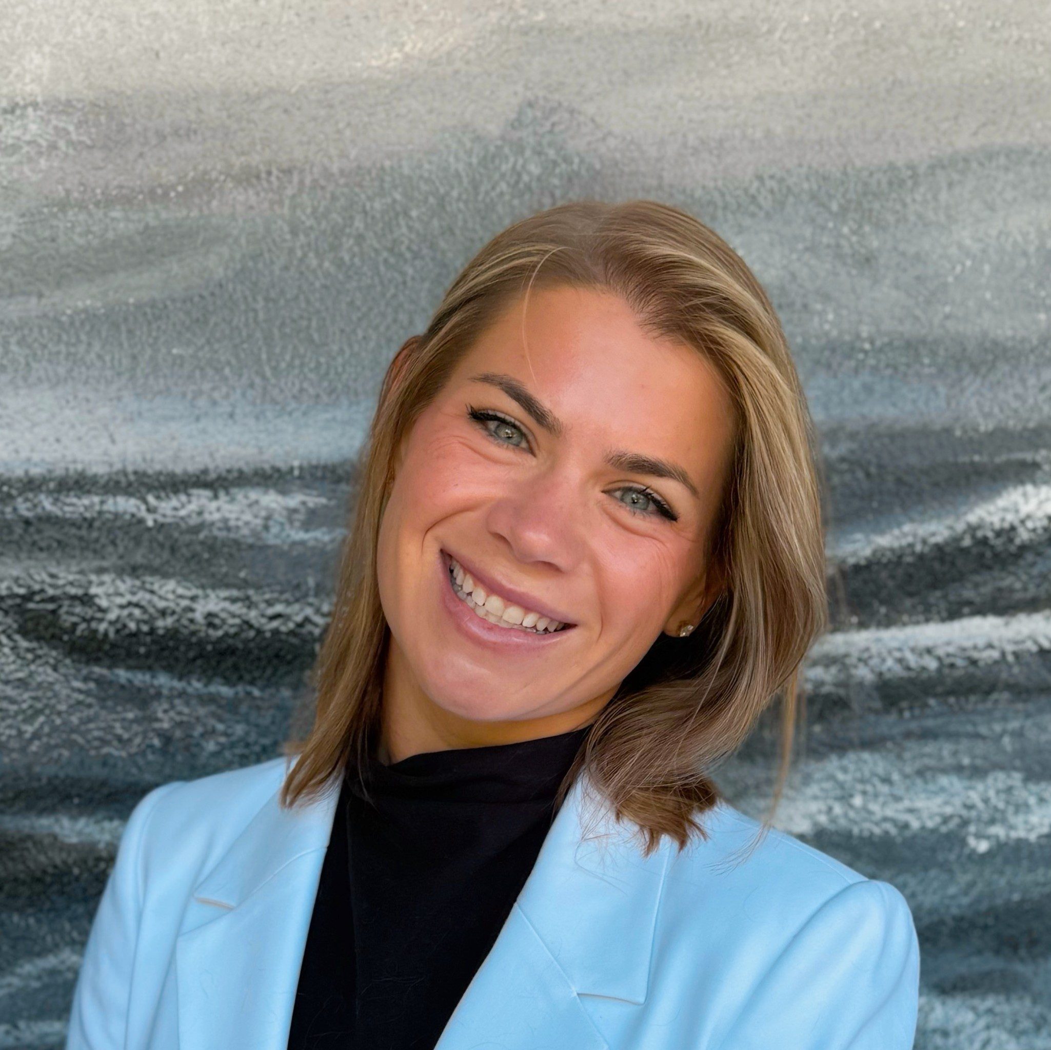 Dr Ellie Tonsich wearing a blue lab coat and smiling at the camera