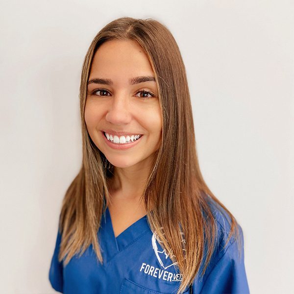 Jess Ferro wearing blue scrubs and smiling at the camera