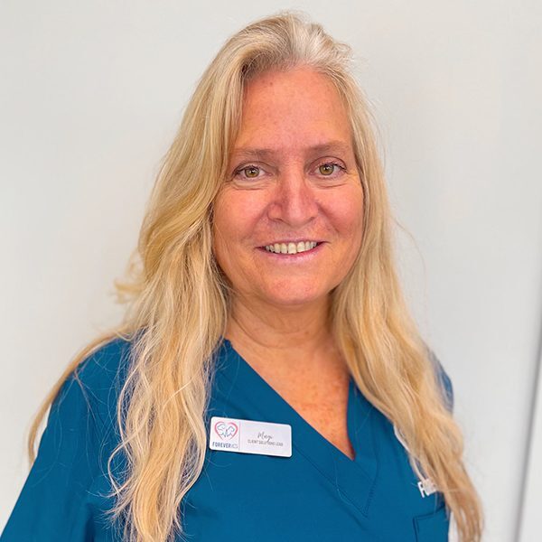 Magi Foster wearing blue scrubs and smiling at the camera