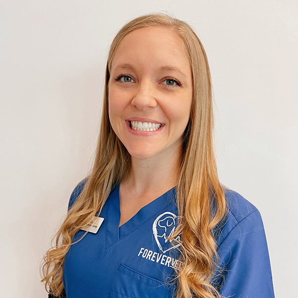 Nicole Evans wearing blue scrubs and smiling at the camera