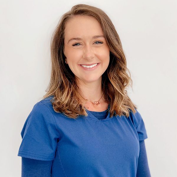 Stormy Davis wearing blue scrubs and smiling at the camera