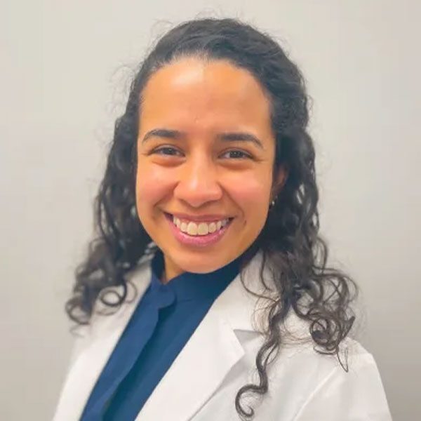 Dr Carolina Collazos wearing a white lab coat and smiling at the camera