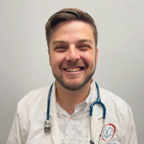 Dr Chris Payne wearing a white lab coat and smiling at the camera