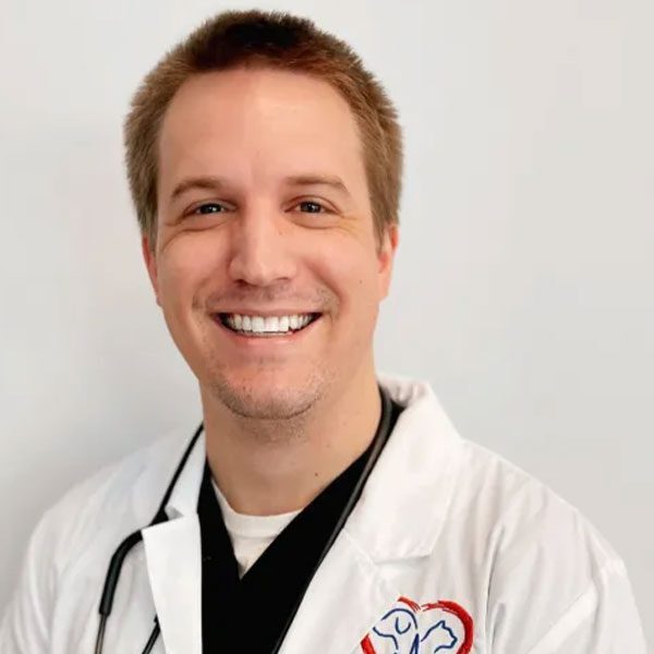 Dr Christopher Dupree wearing a white lab coat and smiling at the camera
