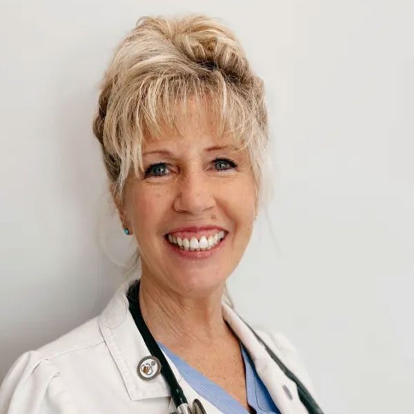 Dr Linda Junk wearing a white lab coat and smiling at the camera