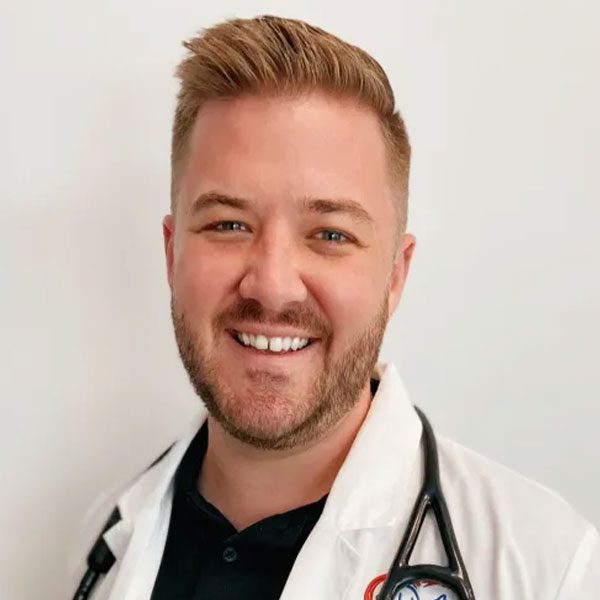 Dr Max Leslie wearing a white lab coat and smiling at the camera