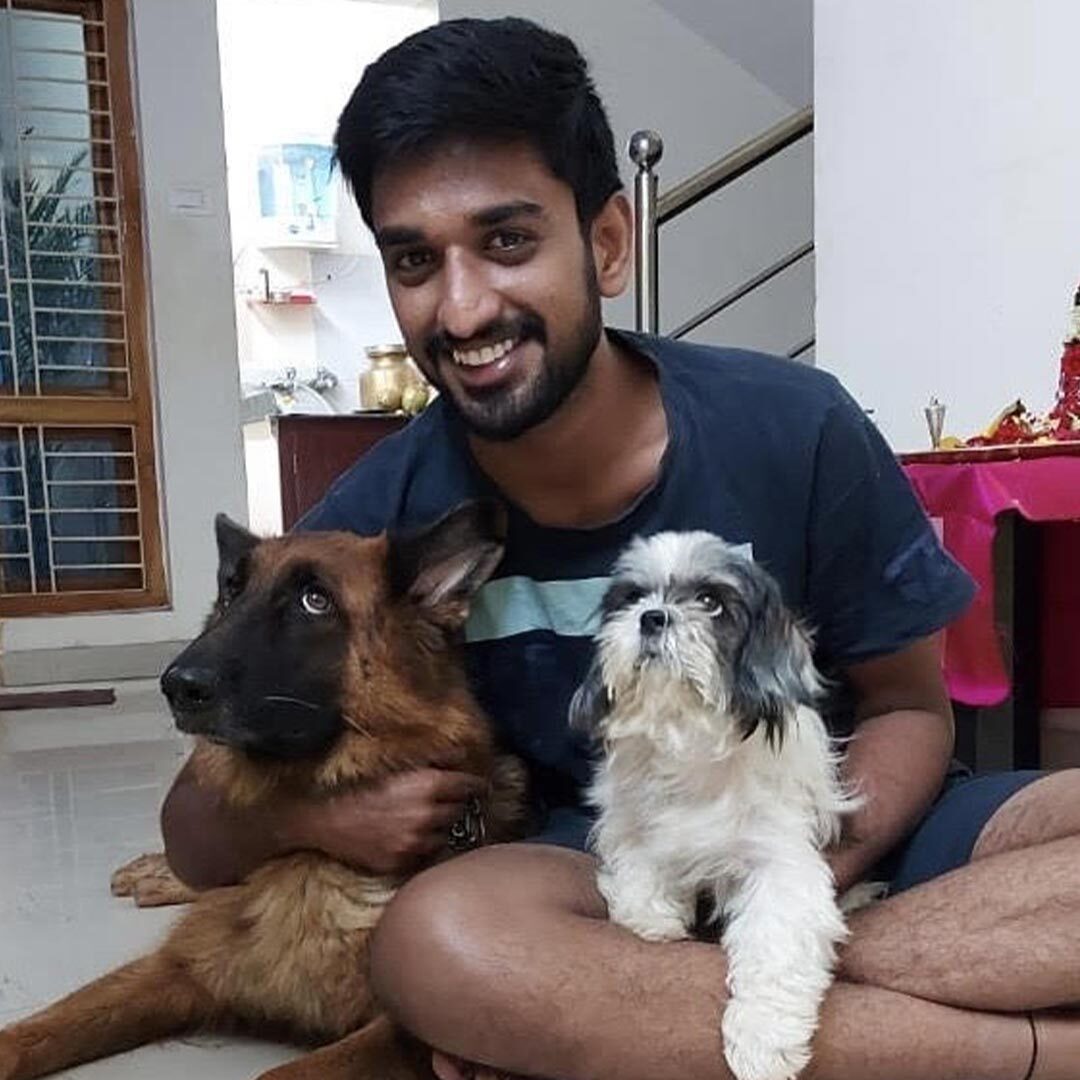 Dr Pavan Uppala hugging his two dogs and smiling at the camera
