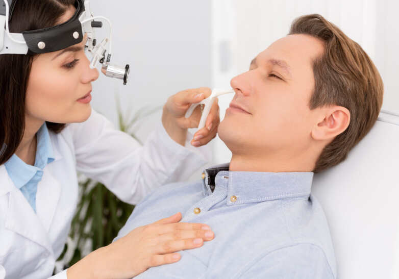 man getting her nose looked at by a doctor