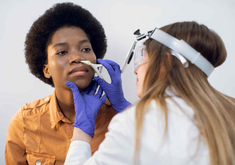 woman getting her nose looked at by the doctor