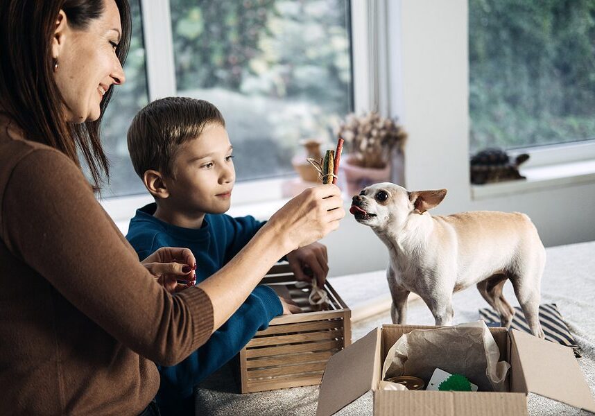 boy and woman giving new toys to their small dog