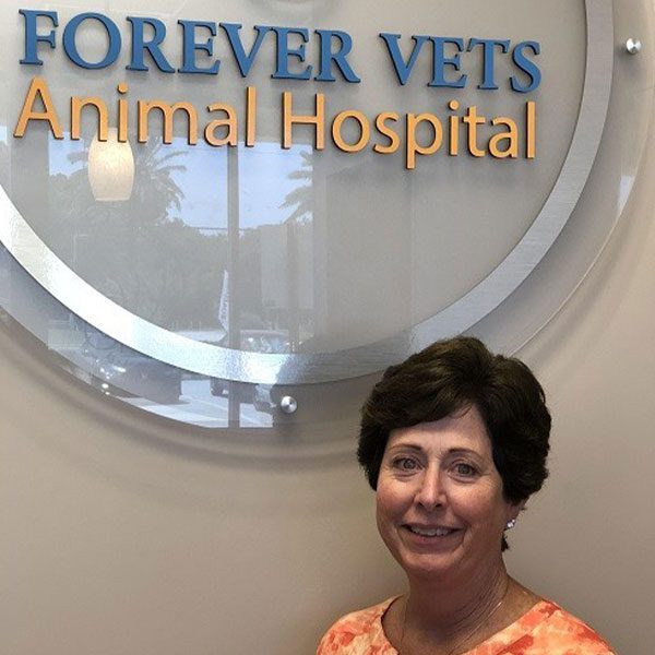 Jane Schaefer next to a forever vets animal hospital logo