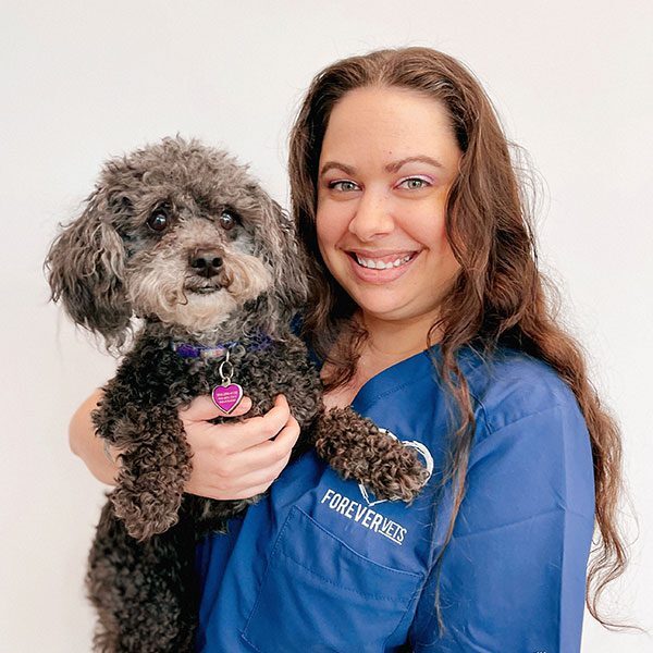 Sarah Papke holding her black dog and smiling at the camera