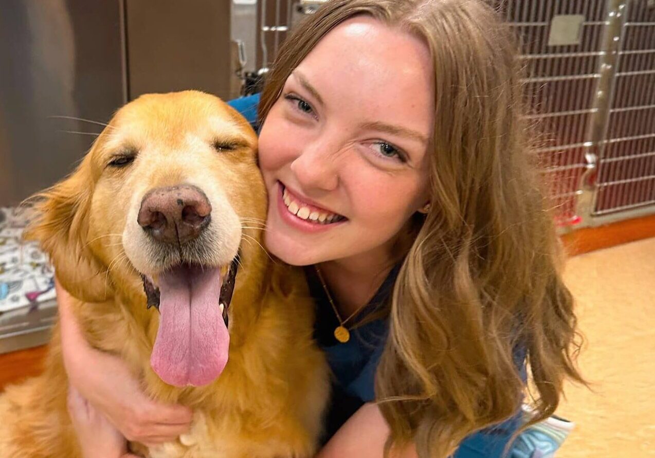 female vet tech smiling with golden retriever