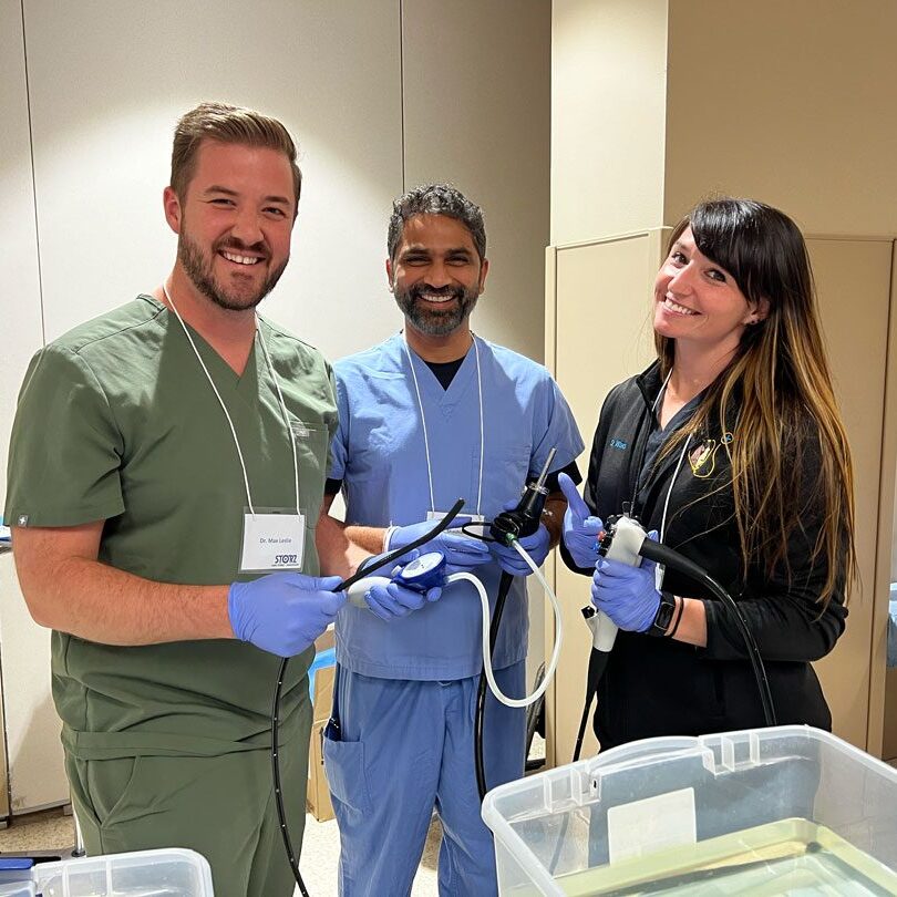 team of three veterinarians smiling and holding equipment