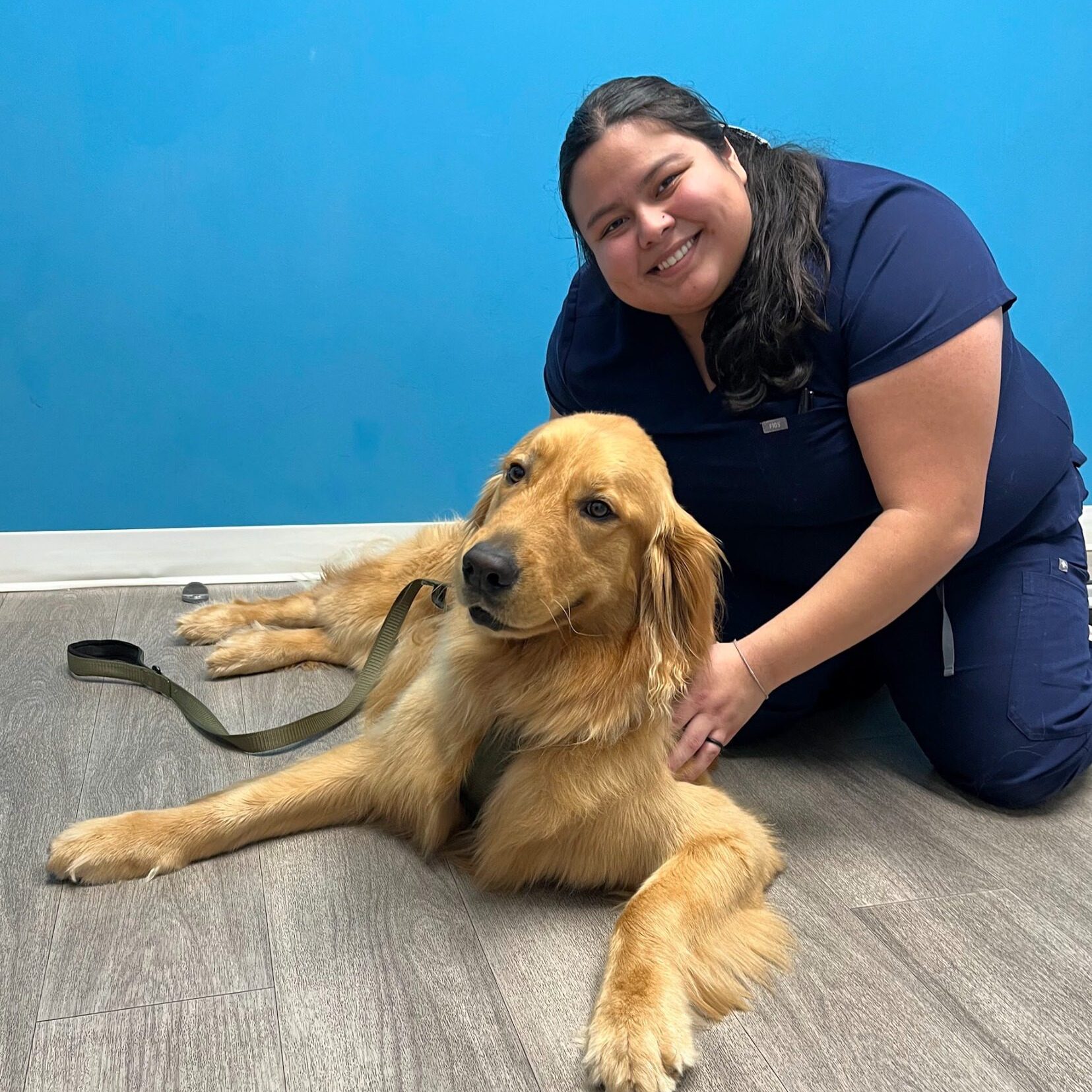 woman on floor smiling with a golden retriever