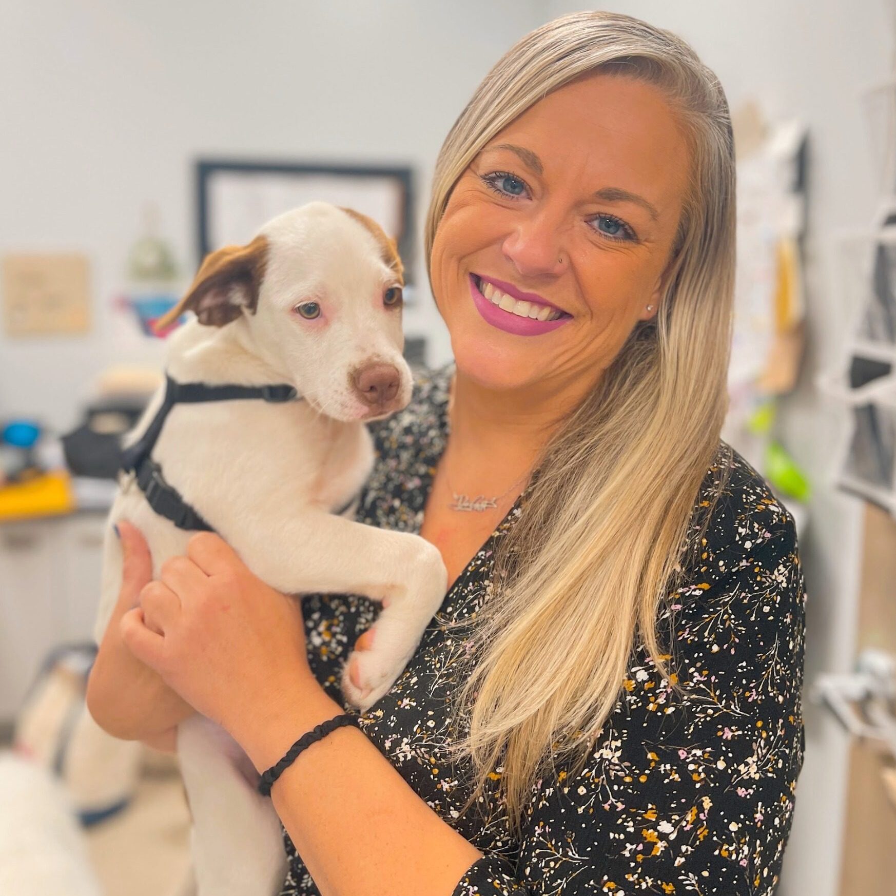smiling woman holding a white puppy